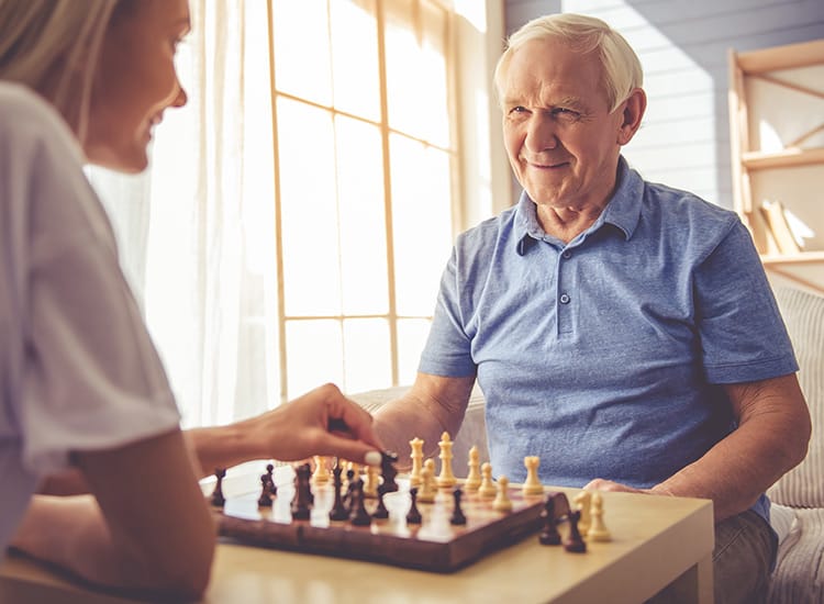 Happy resident engaging in a challenging chess match at Canoe Brook Assisted Living
